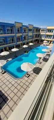 a swimming pool with chairs and umbrellas on a building at Hurghada Aqua-Mirage Beach Resort in Hurghada