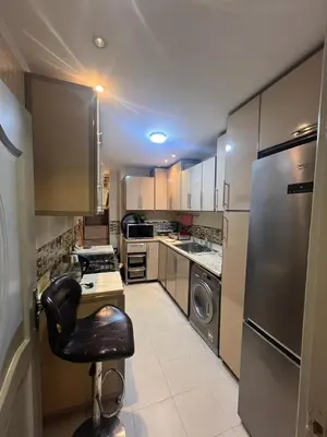 a kitchen with stainless steel appliances and a black chair at Furnished apartment for rent in Abū Tīj