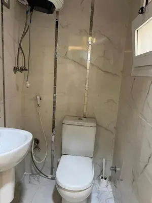 a bathroom with a white toilet and a sink at Furnished apartment for rent in Abū Tīj