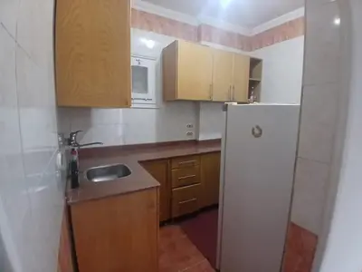 a kitchen with a white refrigerator and wooden cabinets at Rent Mubarak 2 in Hurghada