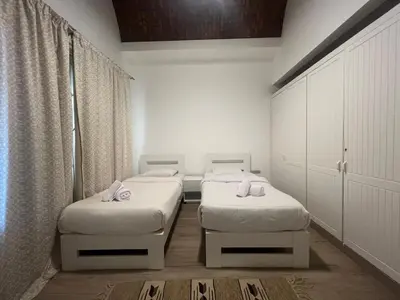 two beds in a room with white walls and curtains at Cozy South Marina 2Bdr with Pool Access in Hurghada