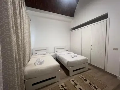 two beds in a room with white walls and curtains at Cozy South Marina 2Bdr with Pool Access in Hurghada