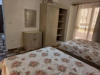 a bedroom with two beds and a dresser and windows at Apartment compound west sayed Al kawthar in Hurghada