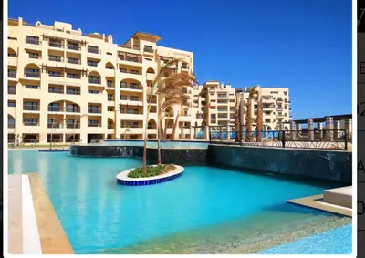 a building with a palm tree in the middle of a pool at Modern simple apartment with roof in Hurghada