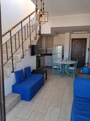 a living room with a blue couch and a kitchen at Modern simple apartment with roof in Hurghada