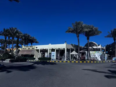 a building with palm trees in front of a street at Stella Makadi Bay - Pool View Apartment with Beach Access - Holiday Makadi in Hurghada