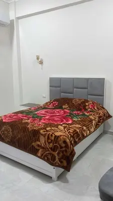 a bed in a white room with a brown blanket at mariam Garden in Al Aqālitah