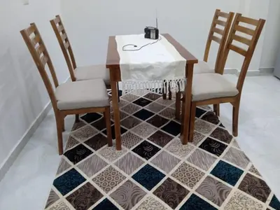 a dining room table with two chairs and a tile floor at mariam Garden in Al Aqālitah