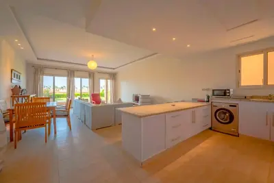 a kitchen with white cabinets and a table and a dining room at Luxury Stays in Golf Town Houses in Hurghada