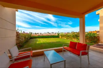 a patio with a red chair and a table and a window at Luxury Stays in Golf Town Houses in Hurghada