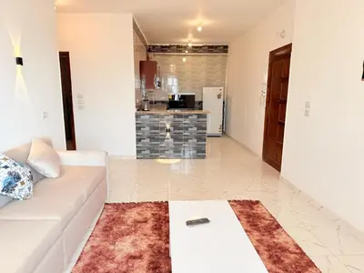 a living room with a white couch and a kitchen at Sun wing guest house in Luxor