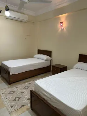 a bedroom with two beds and a light on the wall at شقة ايلا ترافيل in Luxor