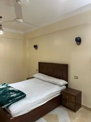 a bedroom with a bed with a wooden headboard at شقة ايلا ترافيل in Luxor