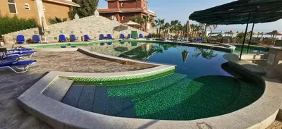 a swimming pool with chairs and an umbrella at Cozy Seaside 1BR Apartment B4 in Turtles Beach - Hurghada in Hurghada