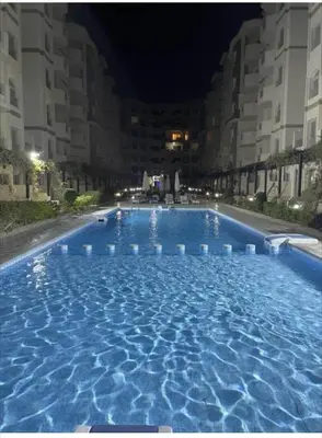 a large swimming pool with blue water at night at Florenza Khamsin Compound Deluxe Apartment C103 in Hurghada