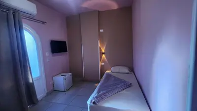 a small bedroom with a bed and a window at Shapon Hotel - Hurghada in Hurghada