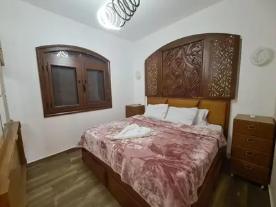a bedroom with a large bed with a wooden headboard at ElGouna west golf 2 bedrooms 2 bathrooms - pool in Hurghada