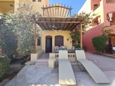a patio with a table and benches in front of a building at ElGouna west golf 2 bedrooms 2 bathrooms - pool in Hurghada