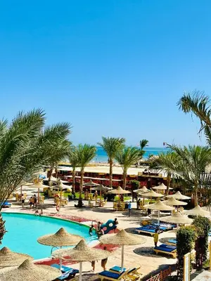 a resort with a pool with umbrellas and palm trees at Azure horizon,Karma Aqua beach resort,Hurghada in Hurghada