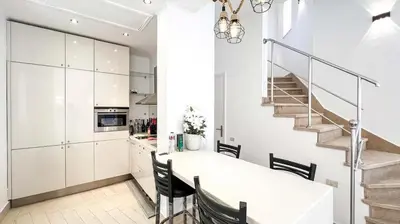 a white kitchen with a dining table and a staircase at Light & Airy Spacious Soma bay Marina 3BR w Sauna & Hot tub in Hurghada