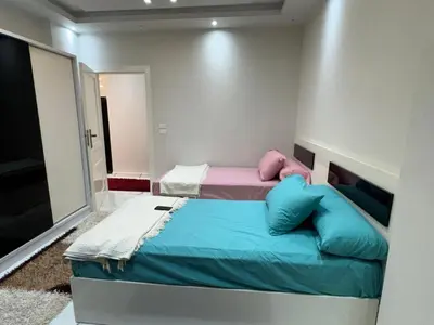 a small bedroom with two beds and a television at 1st Time Rental, 2 BDR Apartment, Pool View, Intercontinental District in Hurghada