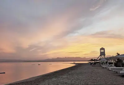 a beach with umbrellas and the ocean at sunset at Panoramic Seaview Somabay 1BR Apartment in Mesca in Hurghada