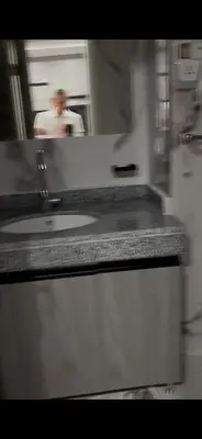 a bathroom counter with a sink and a man in the mirror at غرفه فندقيه in Hurghada