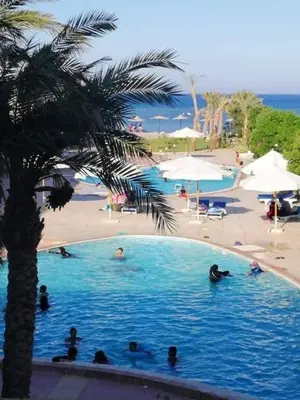 a group of people in a swimming pool next to a beach at cecelia resort in Hurghada
