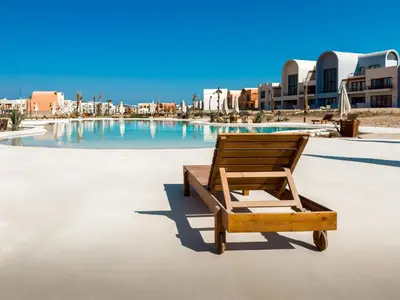 a wooden chair sitting in front of a swimming pool at Gouna Ground-Floor Stylish 2Bdr in Hurghada