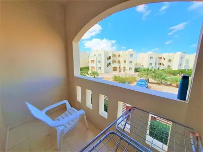 a balcony with a chair and a view of a building at 2BR Makadi heights -cozy Flat in Hurghada