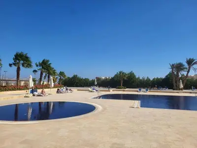 a pair of pools in a park with palm trees at 2BR Makadi heights -cozy Flat in Hurghada