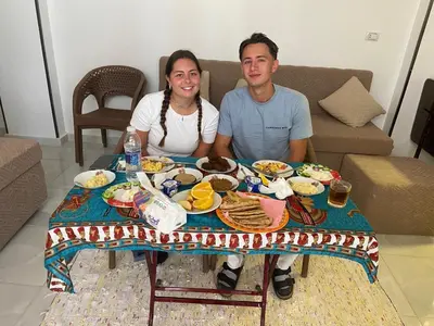 a man and a woman sitting at a table with food at OBAI Nubian Guest House in Aswan