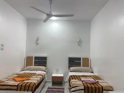 two beds in a room with white walls at OBAI Nubian Guest House in Aswan