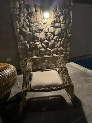 a wicker chair sitting in front of a stone wall at Bali - Elgouna Two Bedrooms private Heated pool in Hurghada