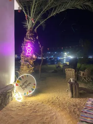 a sign on a beach with a palm tree at night at Bafana Bafana Nile View Guest House in Aswan