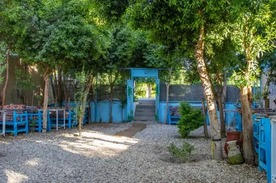 a patio with blue tables and chairs under trees at Pharaohs Rest Luxor in Luxor