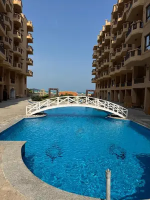 a large pool with a white bridge in front of a building at Turtles Beach Resort Al-Ahyaa in Hurghada