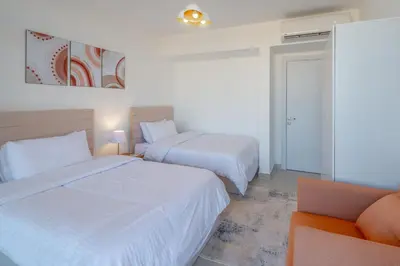 a hotel room with two beds and a couch at 2-Bedroom Penthouse in G-Cribs Gouna in Hurghada