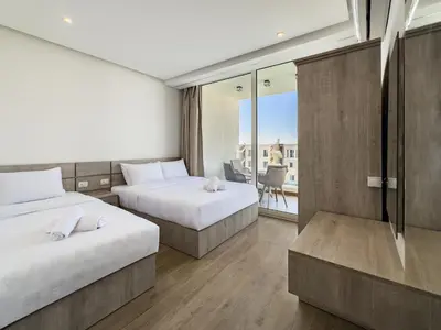a hotel room with two beds and a balcony at Poolside Townhome with 2 Masters, a Huge Terrace in El Gouna in Hurghada