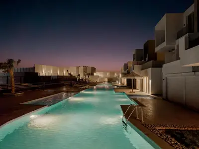 a large swimming pool with blue water at night at Poolside Townhome with 2 Masters, a Huge Terrace in El Gouna in Hurghada