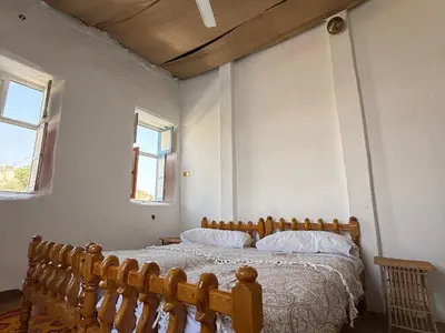 a bedroom with a wooden bed and two windows at Per Ankh - Heissa island - Aswan in Aswan