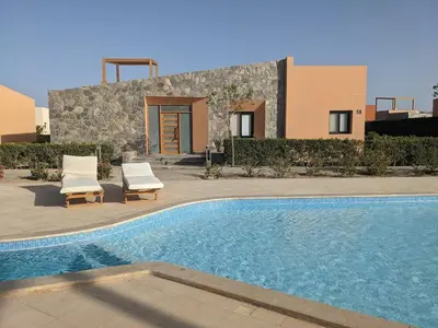 a swimming pool with two chairs and a house at 2BR Pool Front Soma bay Villa Near Mesca Beach in Hurghada