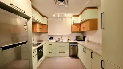 a kitchen with white counters and wooden cabinets at 2BR Pool Front Soma bay Villa Near Mesca Beach in Hurghada