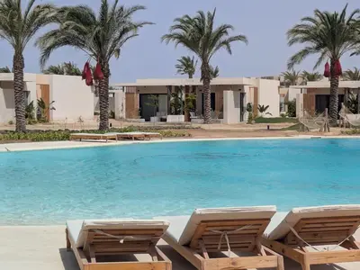 a swimming pool with two lounge chairs in front of a resort at Beachy Pool side Mesca Cabana Somabay Steps to Sea in Hurghada
