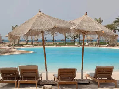 a group of chairs and umbrellas next to a swimming pool at Beachy Pool side Mesca Cabana Somabay Steps to Sea in Hurghada
