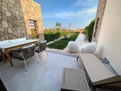 a patio with a table and chairs and a stone wall at Beautiful 2BR Mesca Beach Front Loft in Soma bay in Hurghada