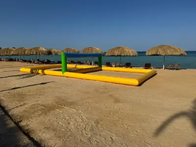 a yellow slide on a beach with chairs and umbrellas at Aquatic Village - Red Sea Resort in Hurghada