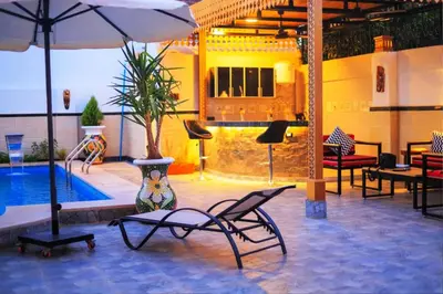 a patio with a pool and chairs and an umbrella at Hamed's House Luxor in Luxor