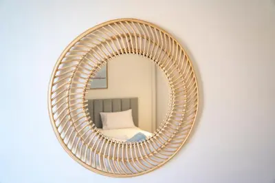 a rattan mirror with a rattan frame on a wall at Bright & Elegant 2BR Retreat - Kamaran El Gouna in Hurghada