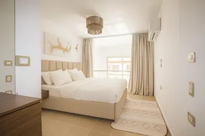 a white bedroom with a bed and a window at Modern Sahl Hasheesh Pool Duplex - Beach & Wi-Fi in Hurghada